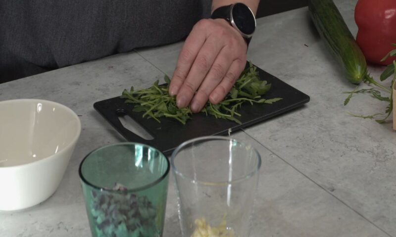 osoba seče rukolu na dasci u kuhinji